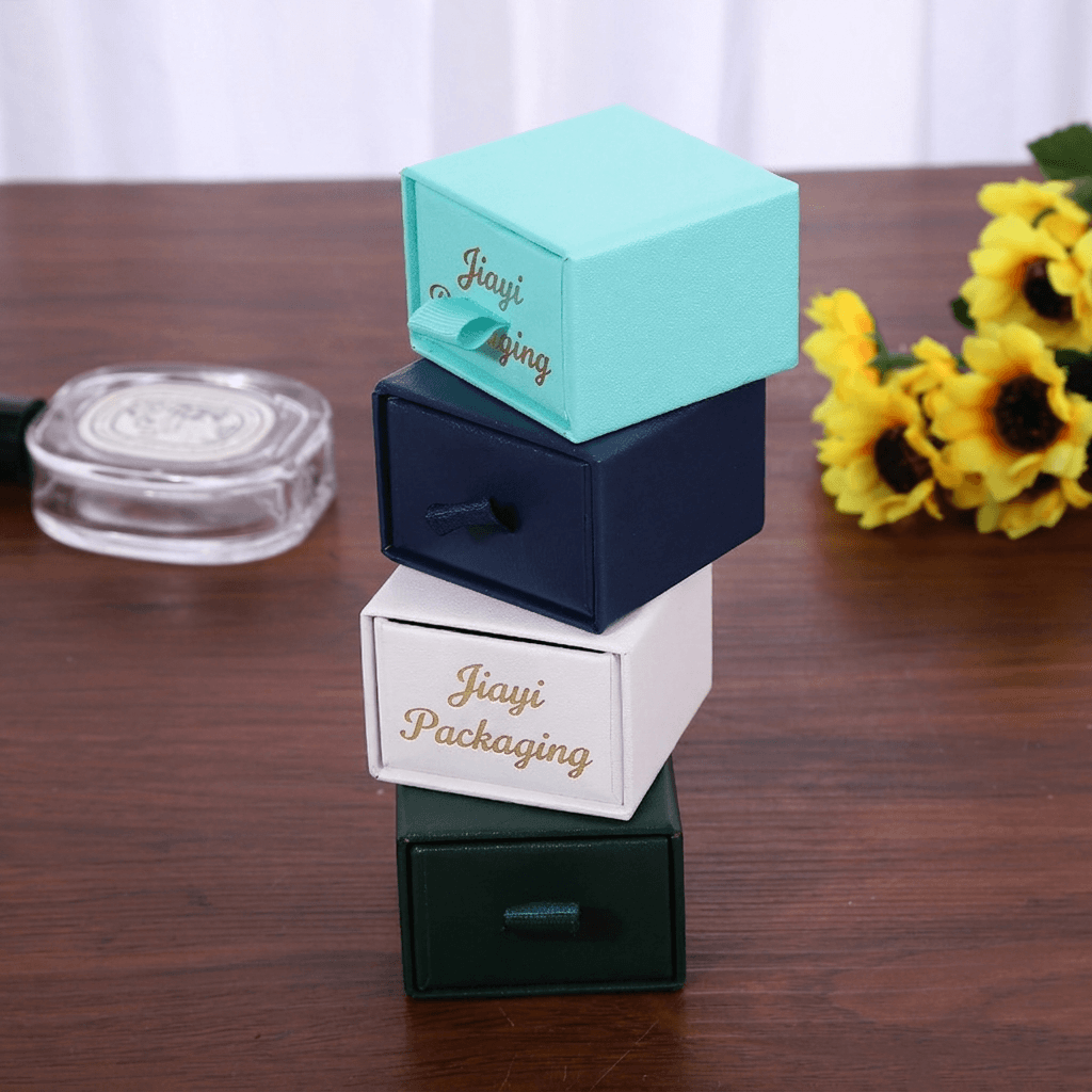 Stacked aqua, navy, white and green jewelry drawer boxes with ribbon pulls