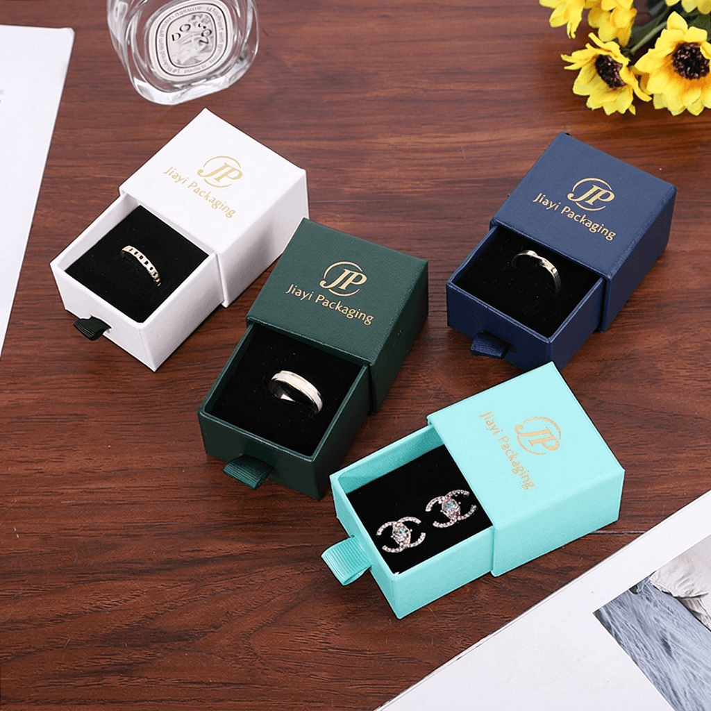 White, green, navy and aqua jewelry drawer boxes opened to show rings and earrings