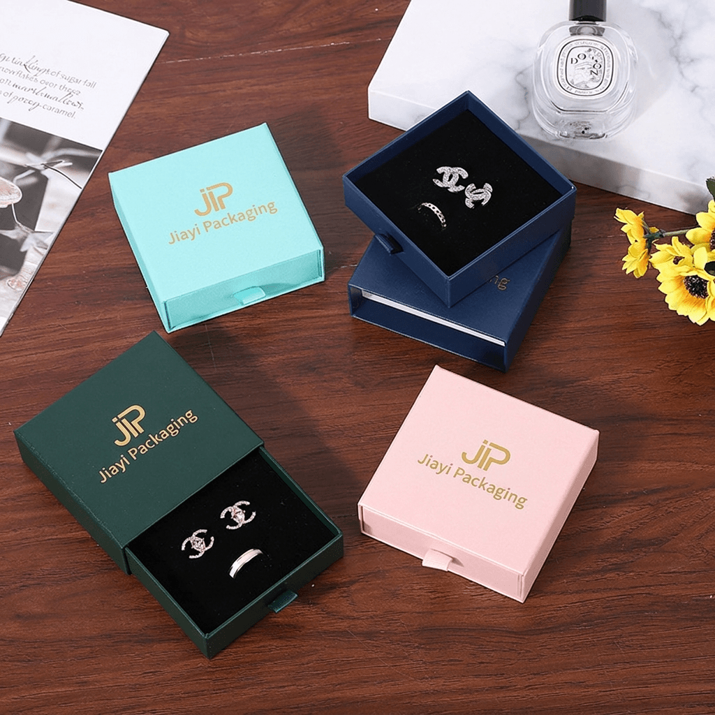Aqua, green, pink and navy jewelry drawer boxes, some open with rings and earrings