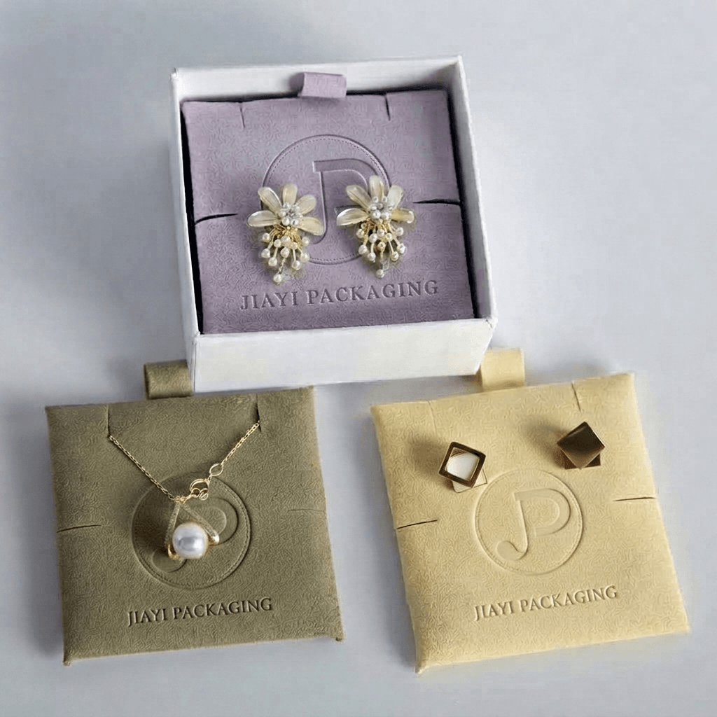 Lavender velvet jewelry pad inside a white rigid box, with olive and cream pouches