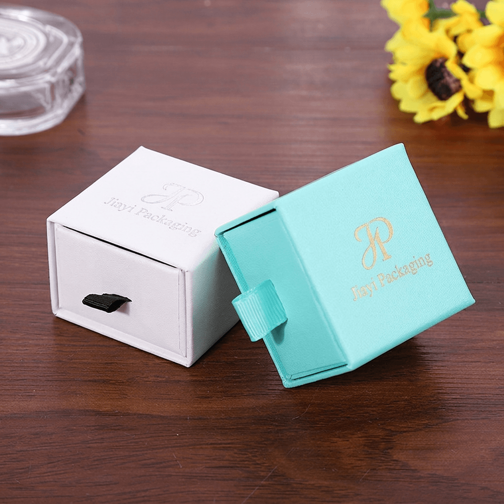 White jewelry drawer box beside an aqua drawer box with the tray open