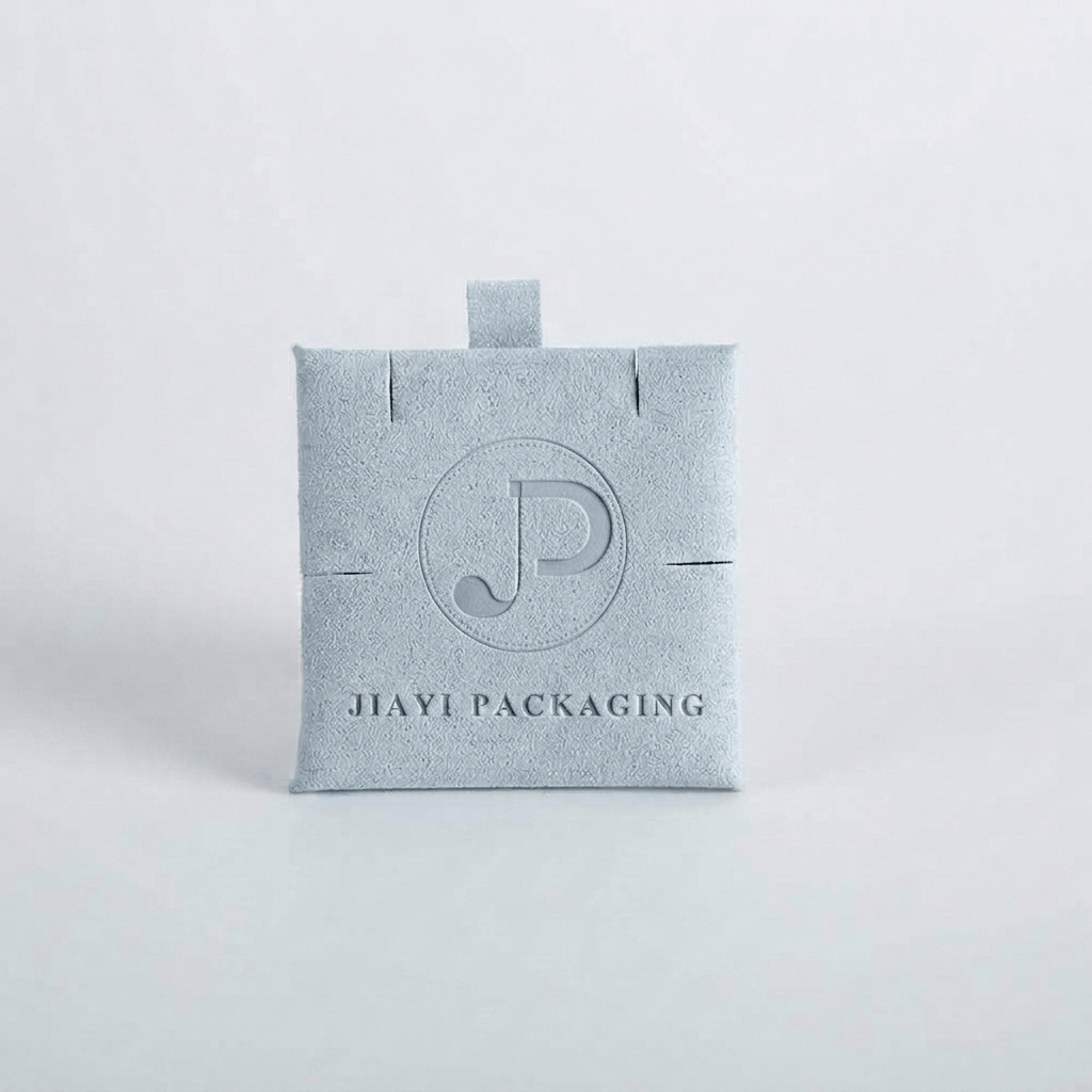 Light blue velvet jewelry pouch with a debossed monogram and top tab